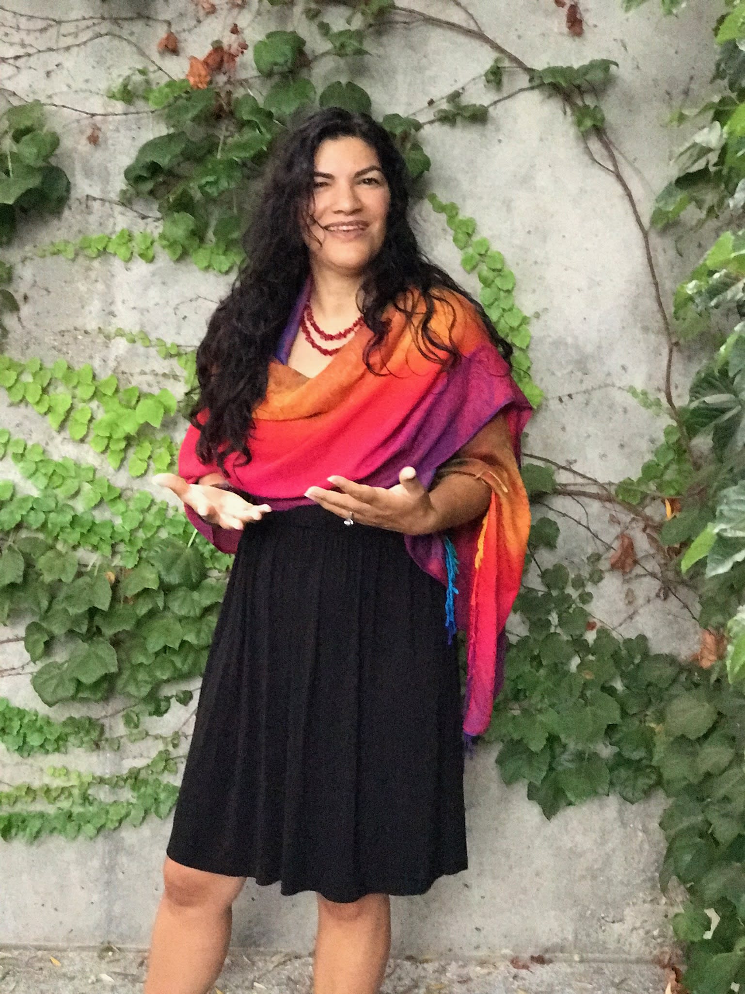 Ymasumac Marañon standing in front of a living vine wall with arms open open